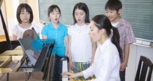 Piano teacher teaching kids to sing